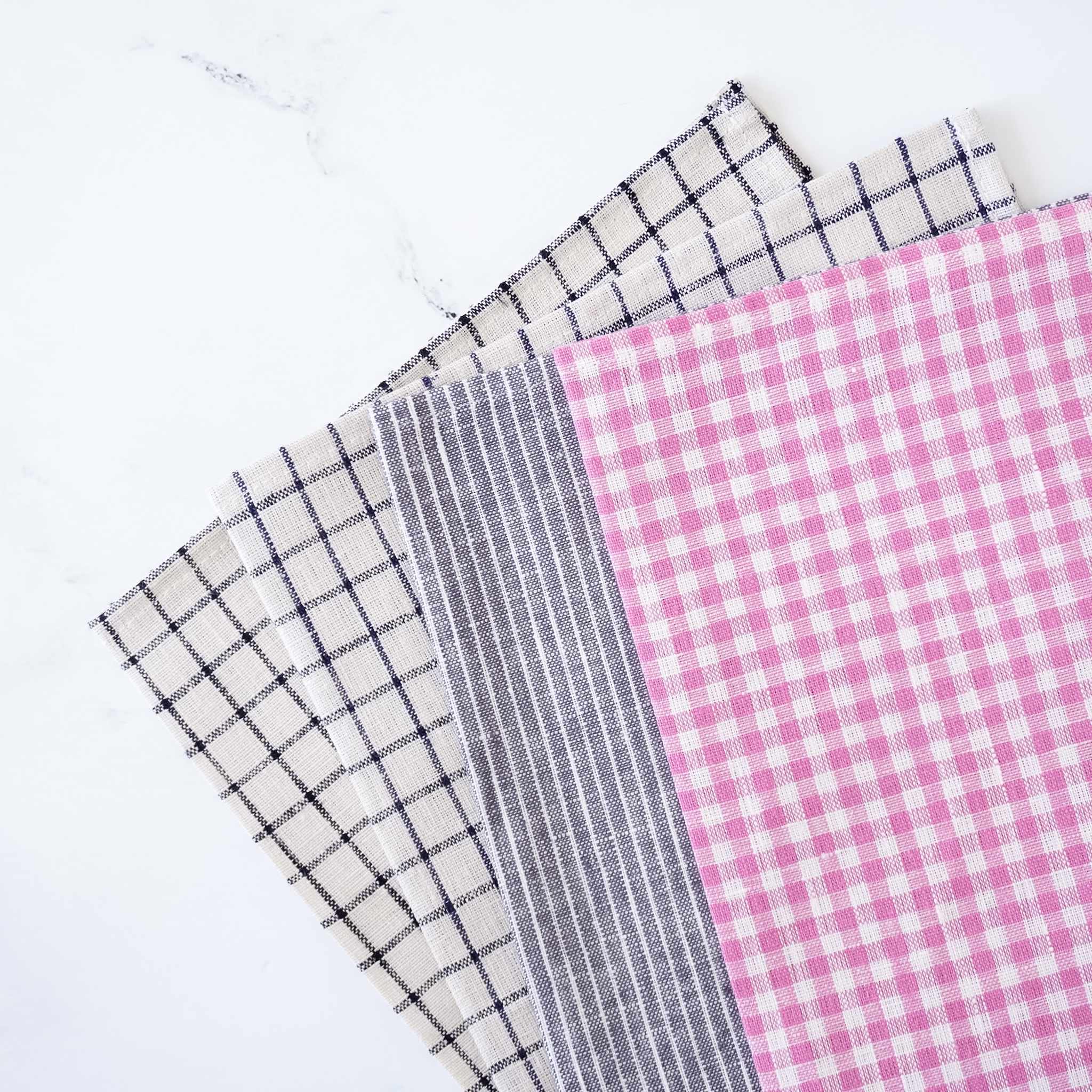 Four linen fabric placemats with different patterns on a white background