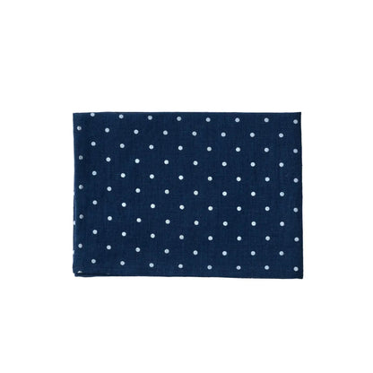 A folded navy blue linen kitchen cloth, featuring a white polka dot pattern, shown against a plain white back ground.