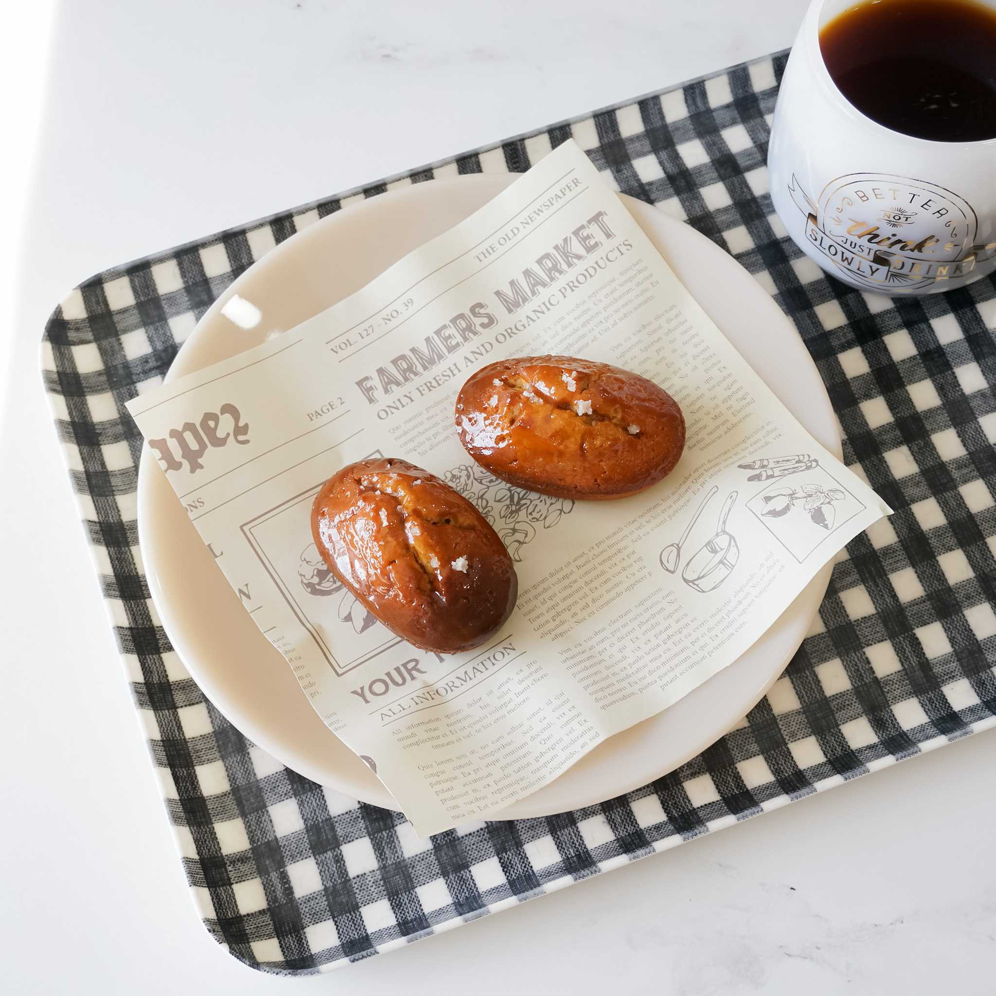 financier cake, newspaper print deli paper, and a serving tray