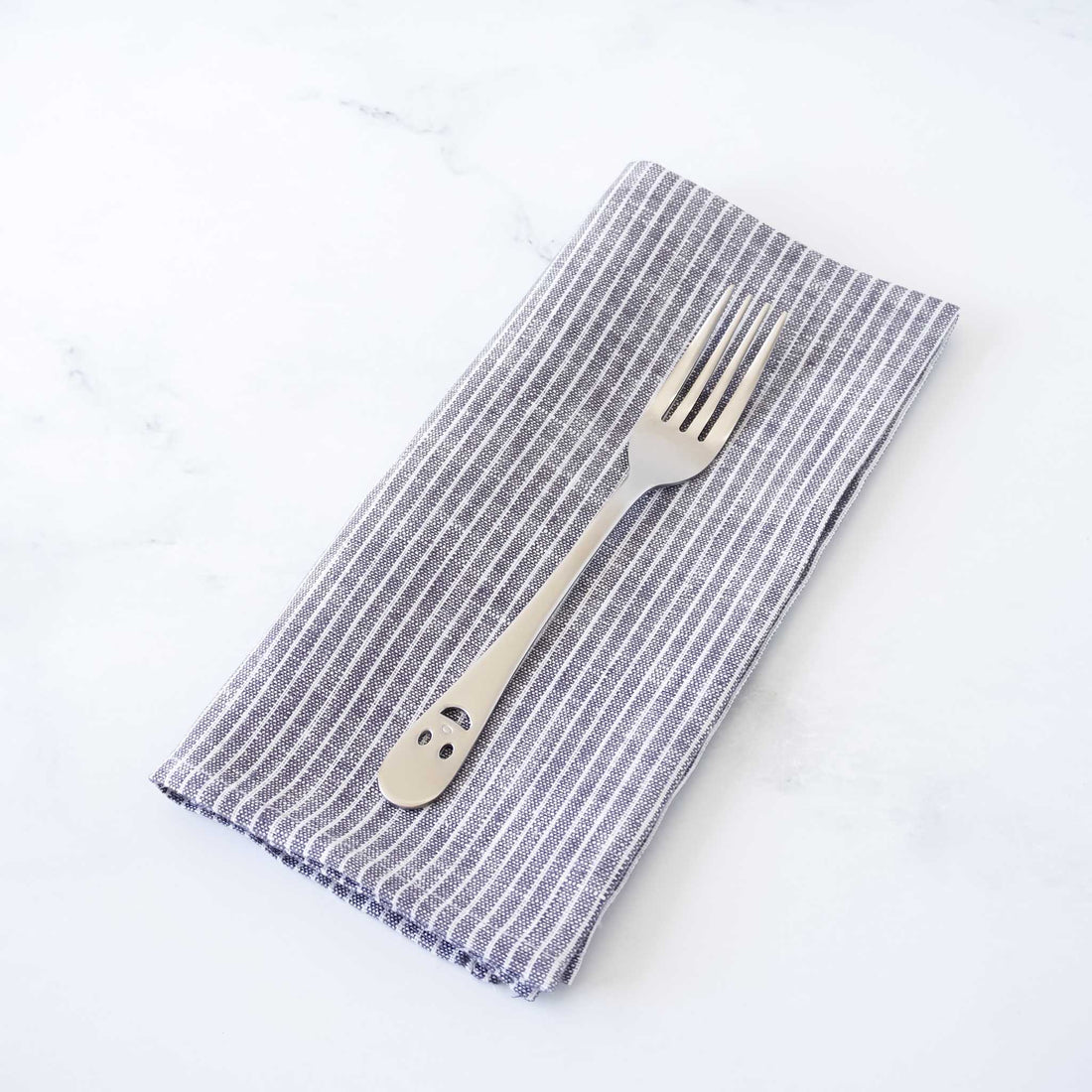 Folded striped napkin with a fork on a white background