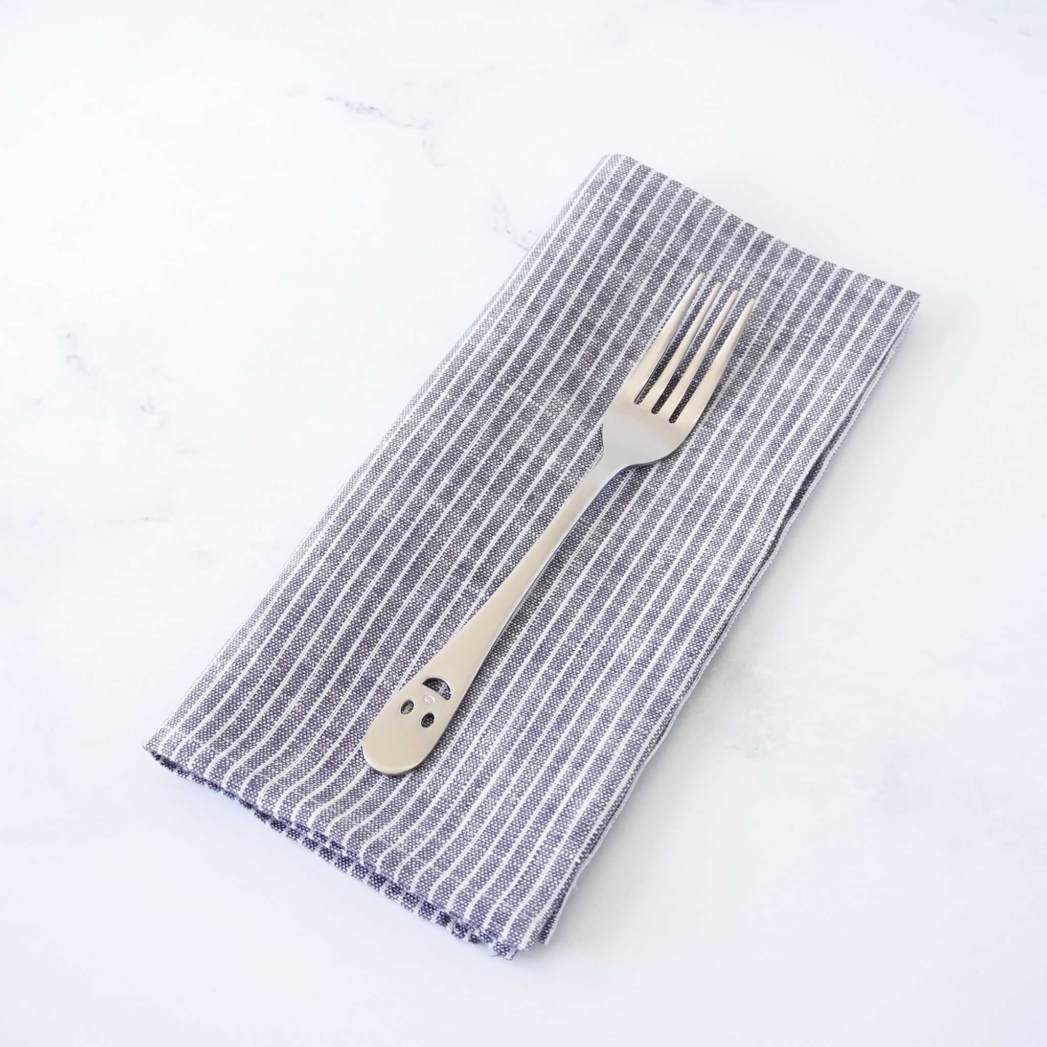 Folded striped napkin with a fork on a white background