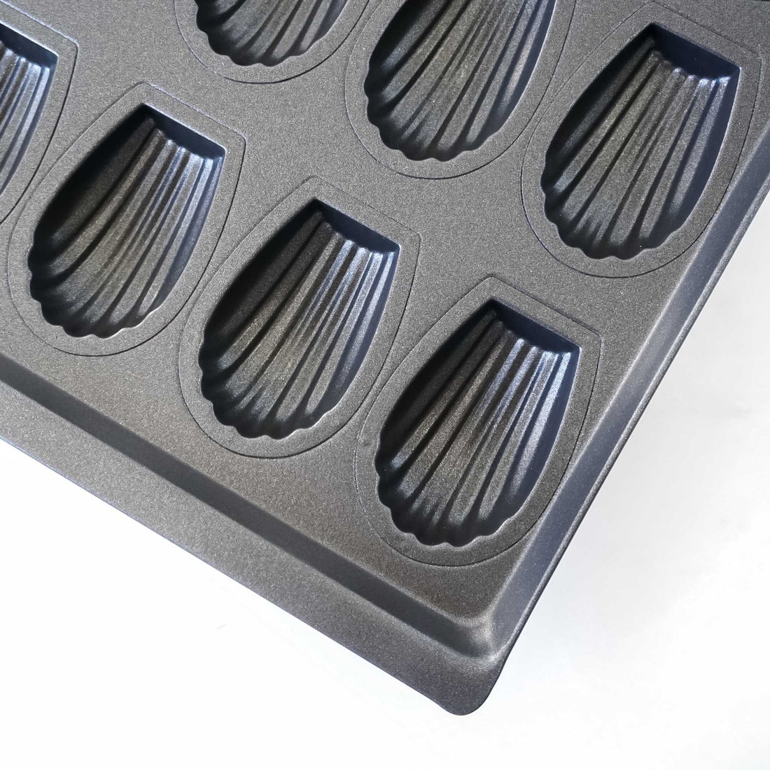 Black madeleine cake mold on a white background