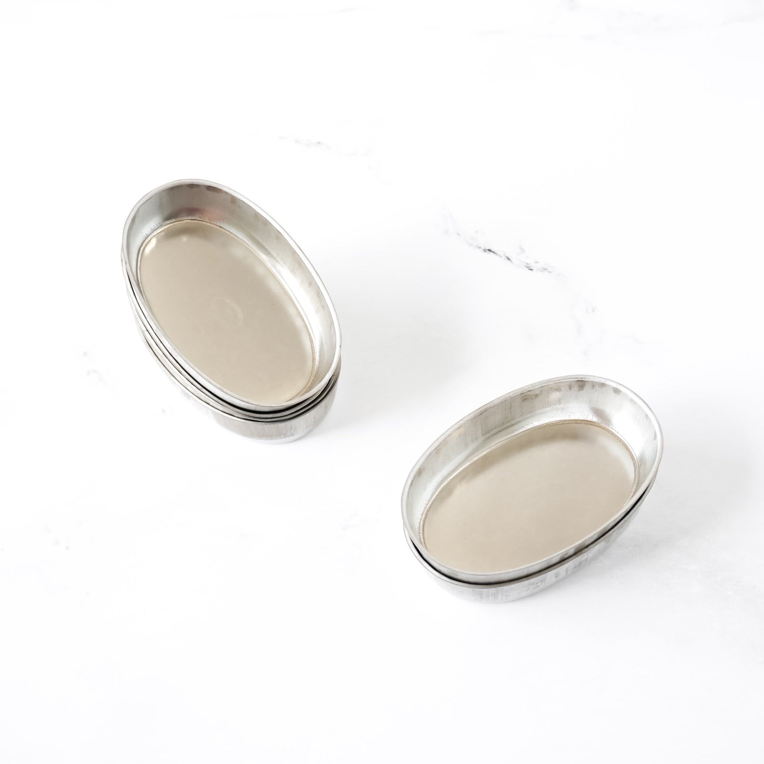 Two oval metal baking pans on a white background