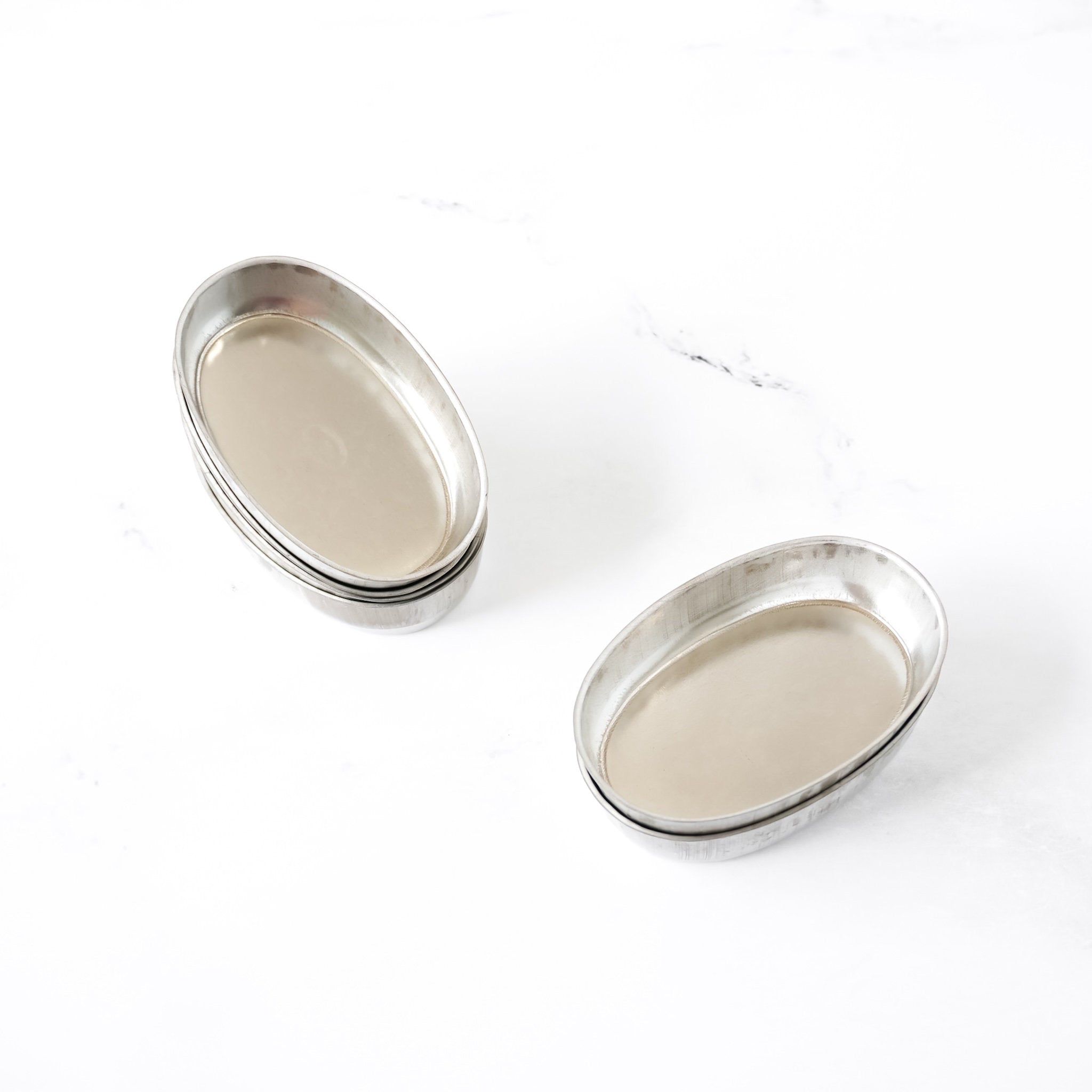 Two oval metal baking pans on a white background