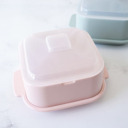 Pink plastic steamer with a lid on a white surface