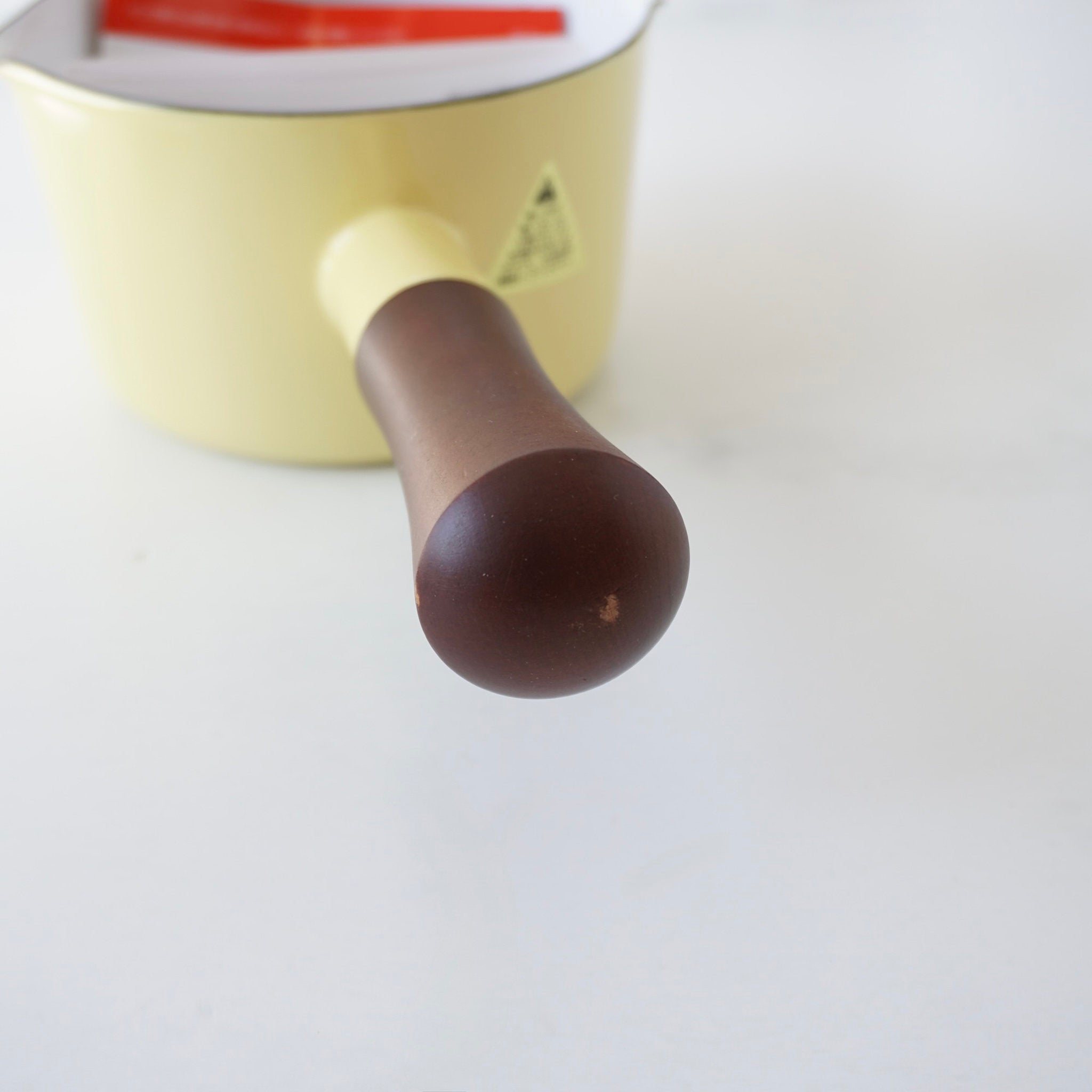 Close-up of a yellow pot with a brown handle on a white background