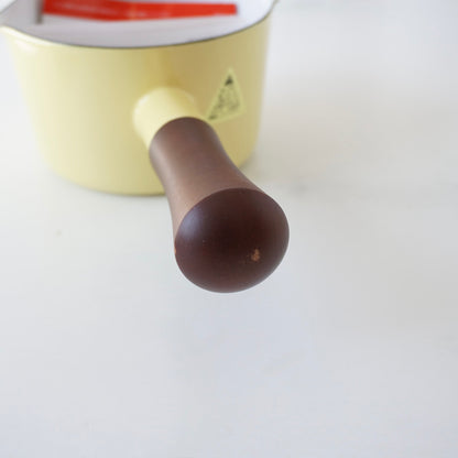 Close-up of a yellow pot with a brown handle on a white background