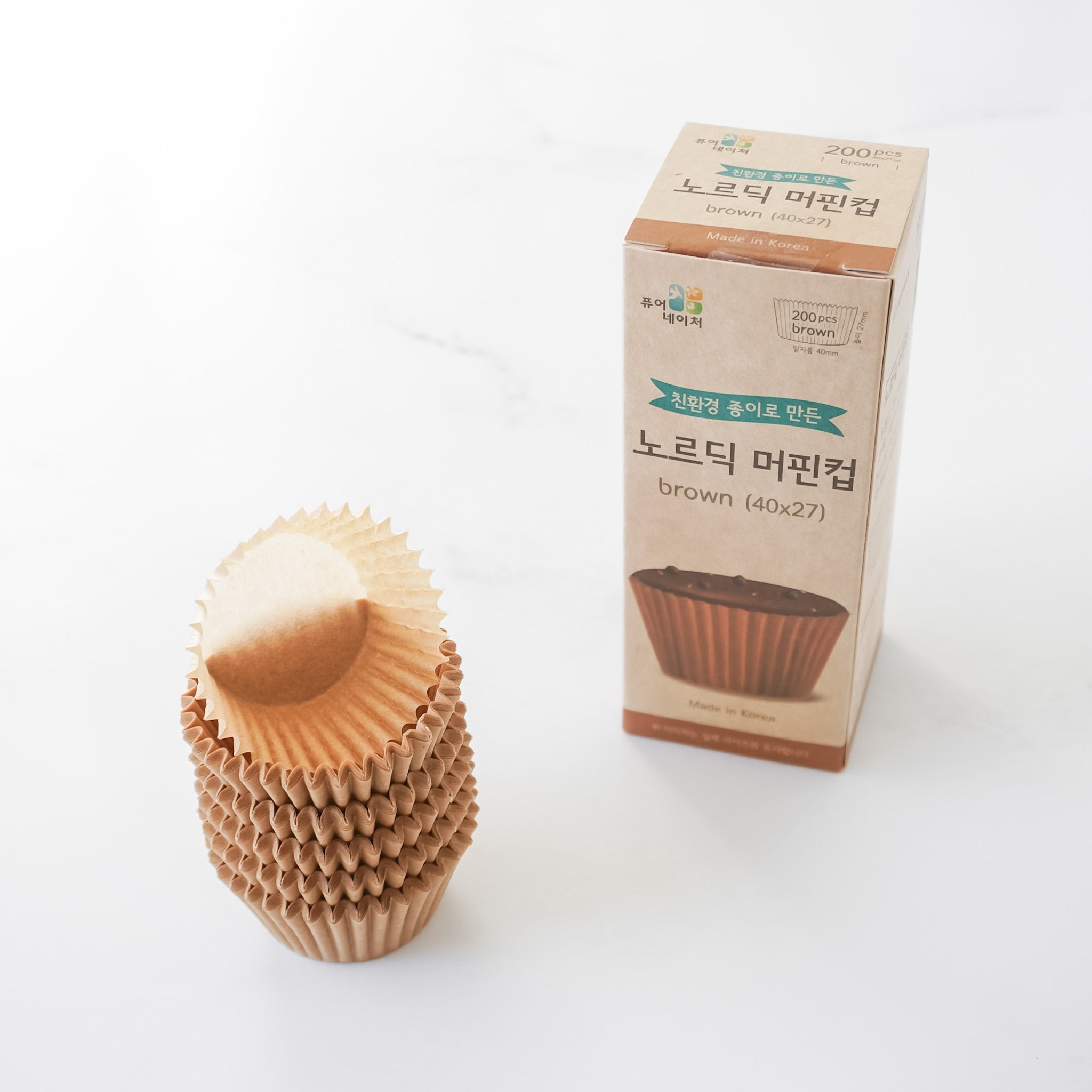 Stack of brown paper muffin cups with a box on a white background