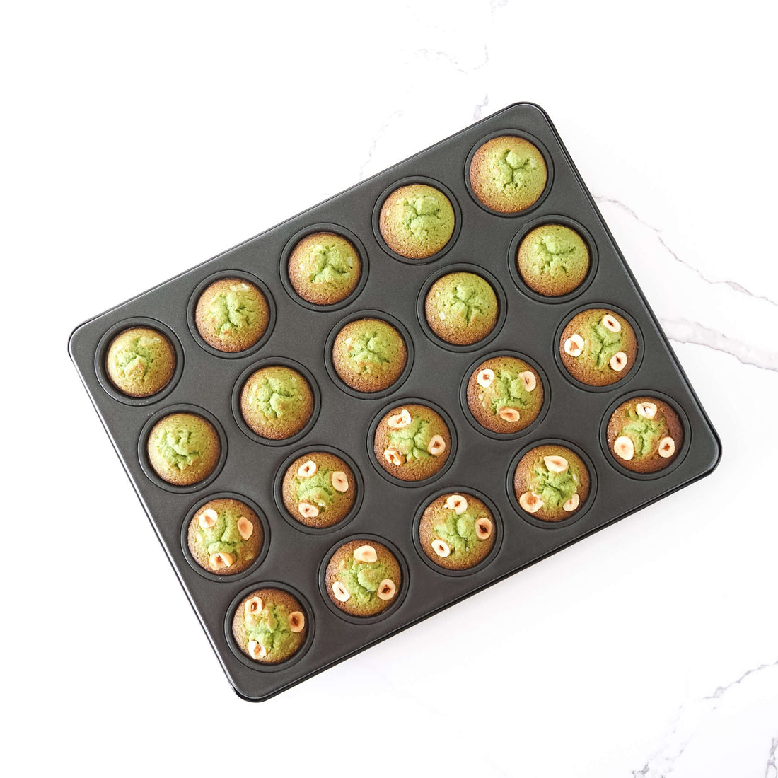 Muffin tray with green muffins on a white background