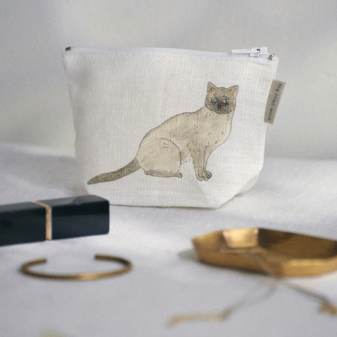 Small linen pouch with a cat illustration on a light surface