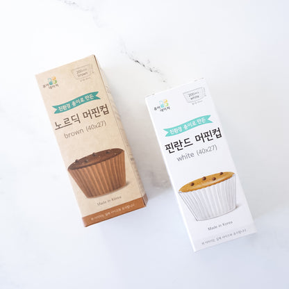 Two boxes of muffin cups, one brown and one white, on a white background.