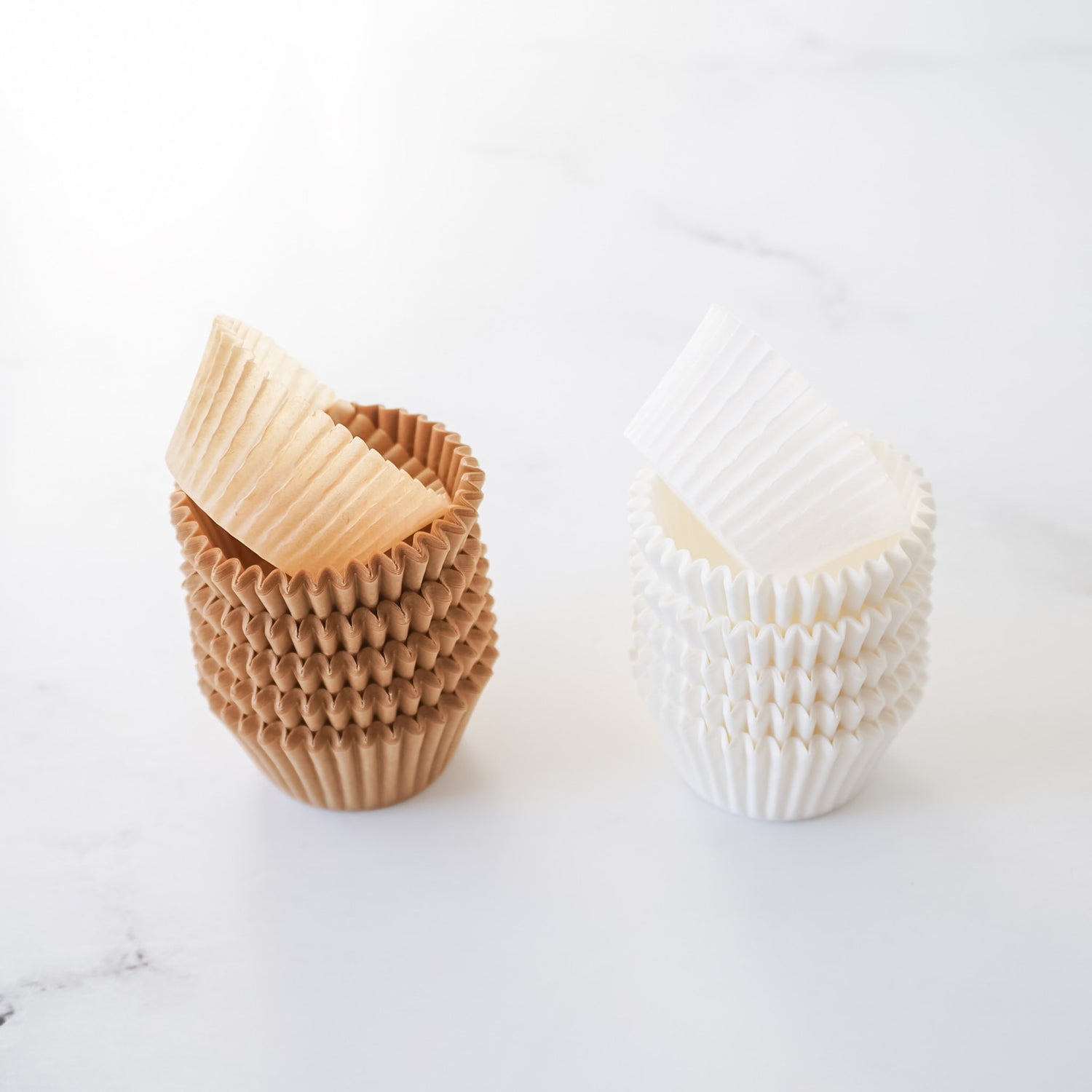 Two cupcake liners, one brown and one white, on a light gray background.