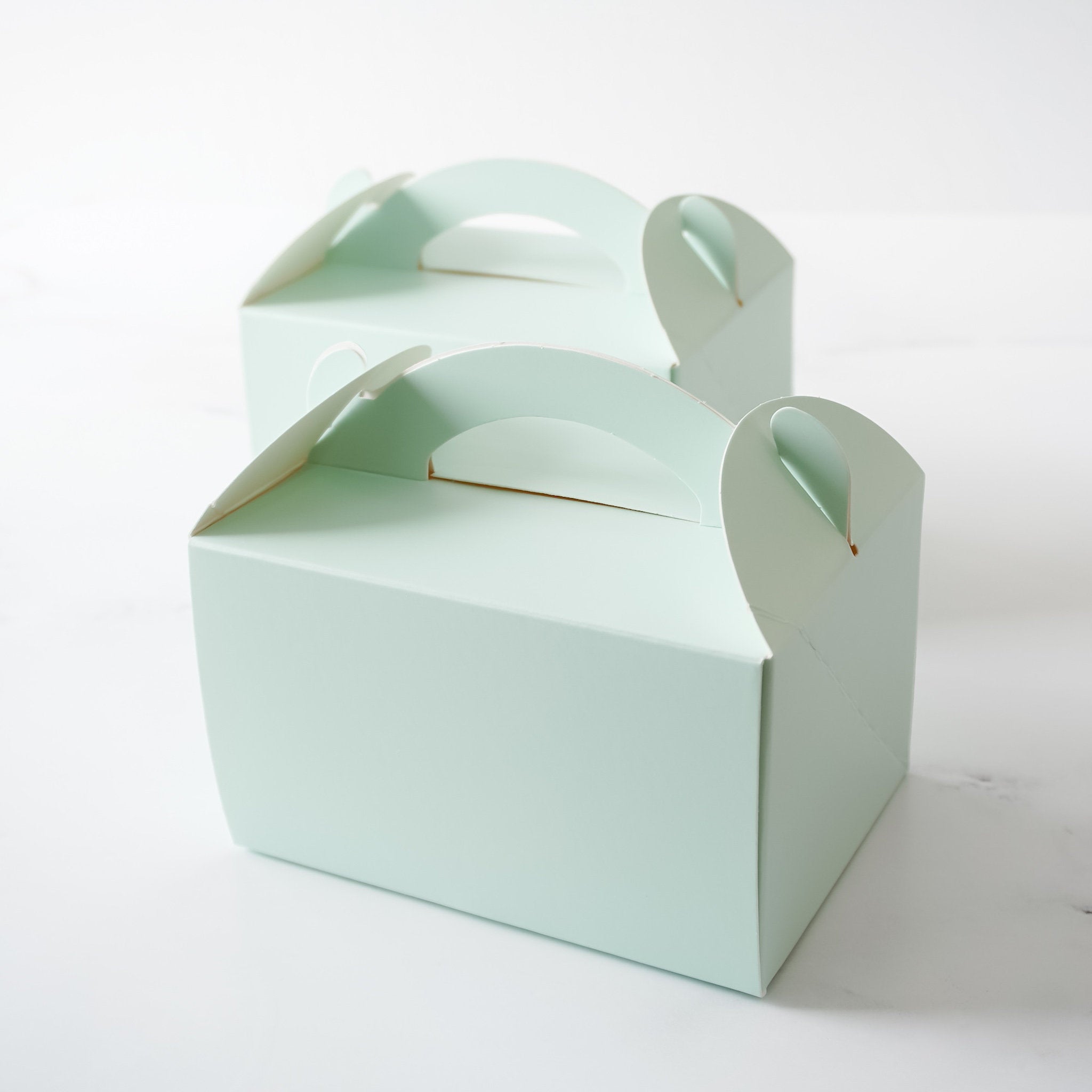Mint green gable boxes with a handle, made from matte-coated food-safe paper, displayed unassembled.