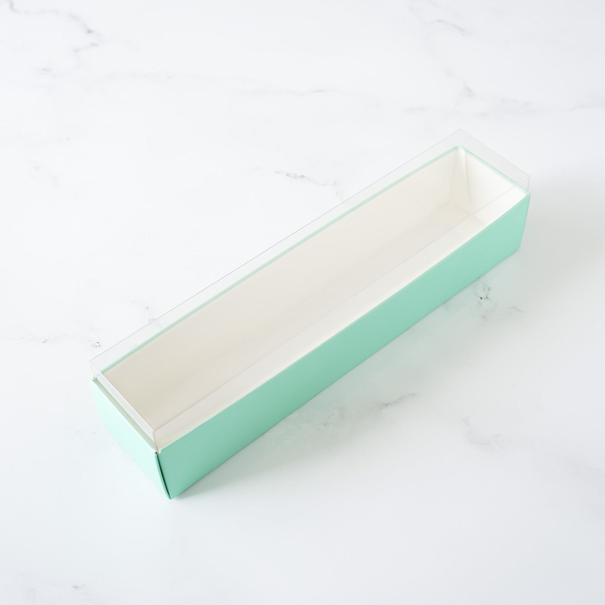 A light green cardboard box with a clear plastic top. The box is empty and has a white interior.