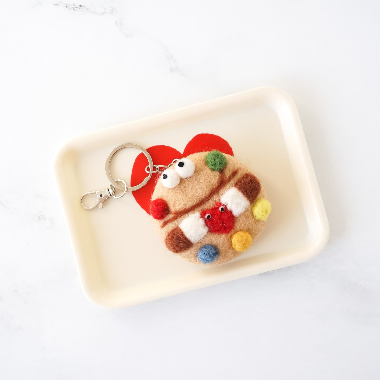 mnm cookie shaped felt keychain on a tray