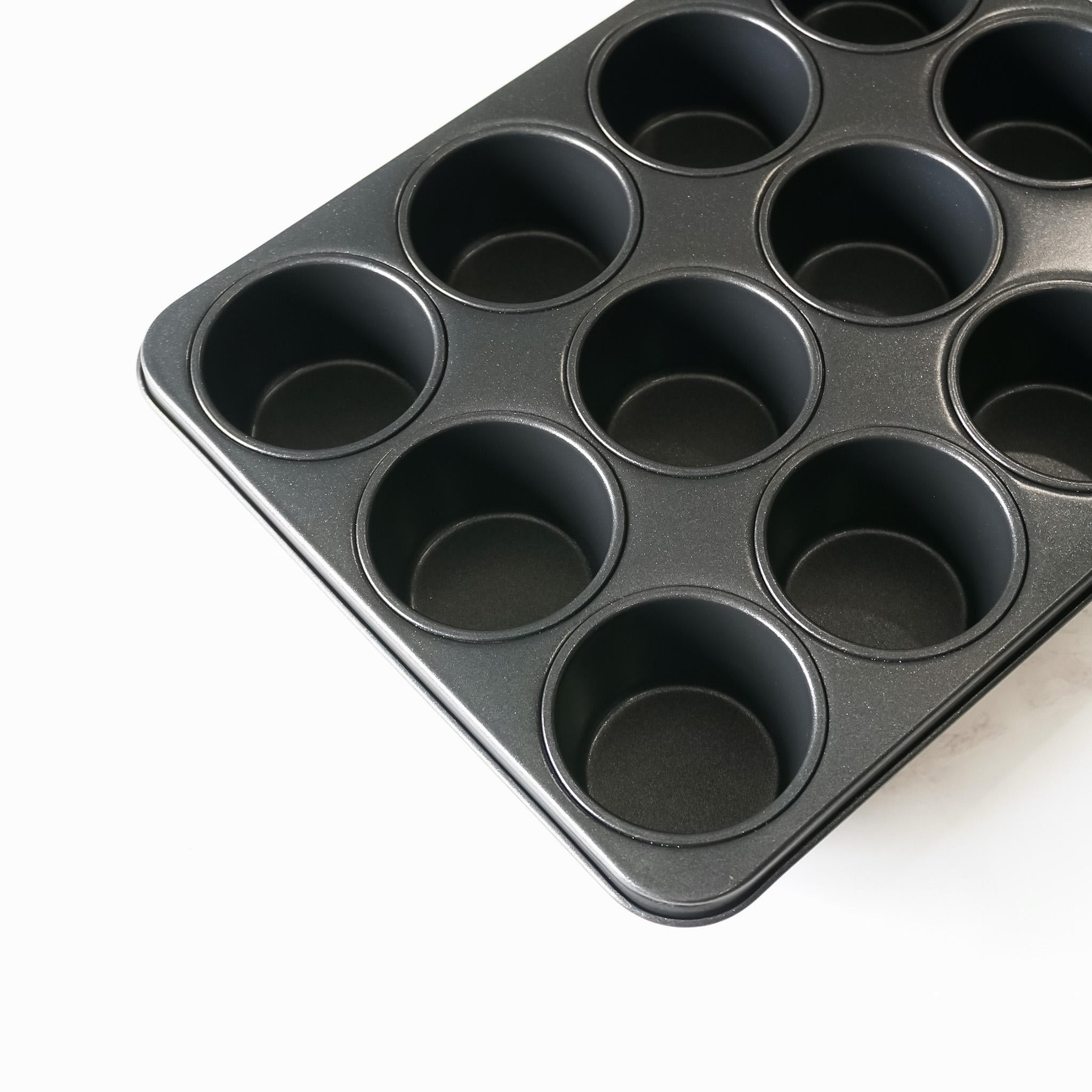 A black metal muffin mold with 12 round cavities. The mold is empty and ready for baking.