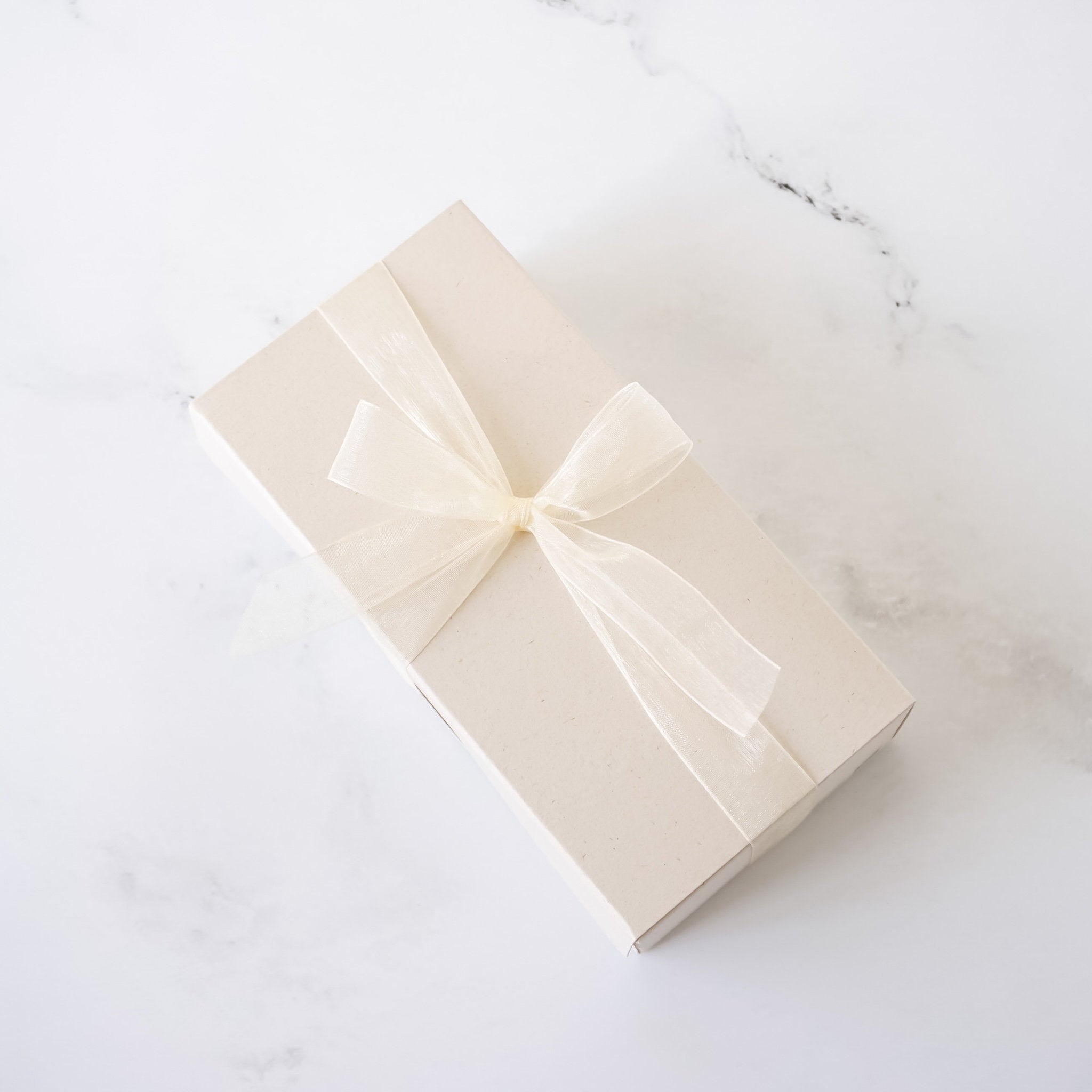 Beige gift box with a bow on a white marble surface