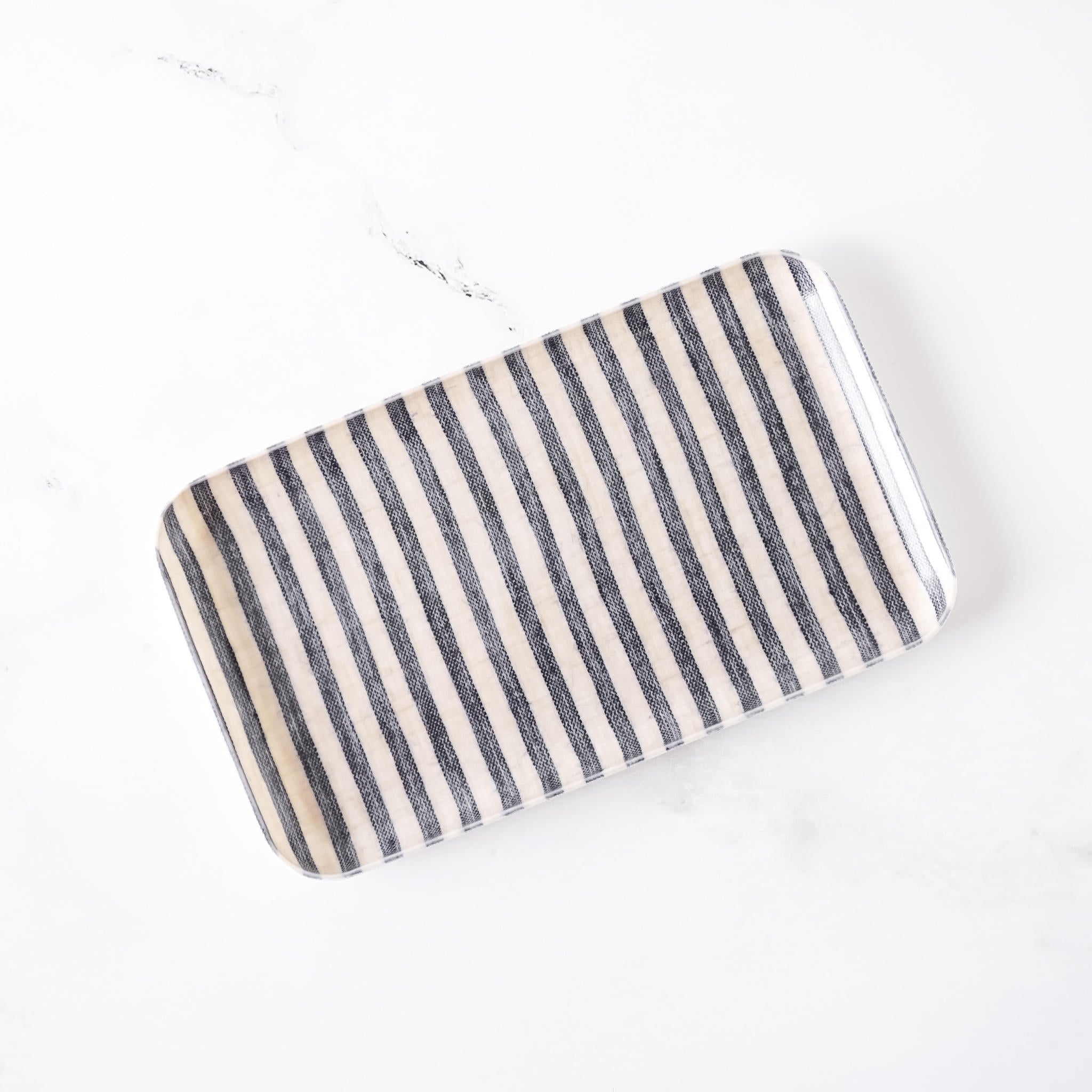 Rectangular poly resin tray with black and beige striped pattern on a white background