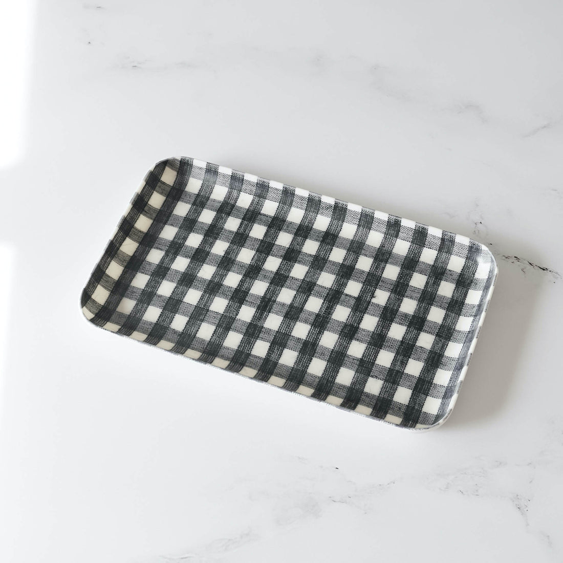 A dark navy check linen coated tray placed on a white surface.