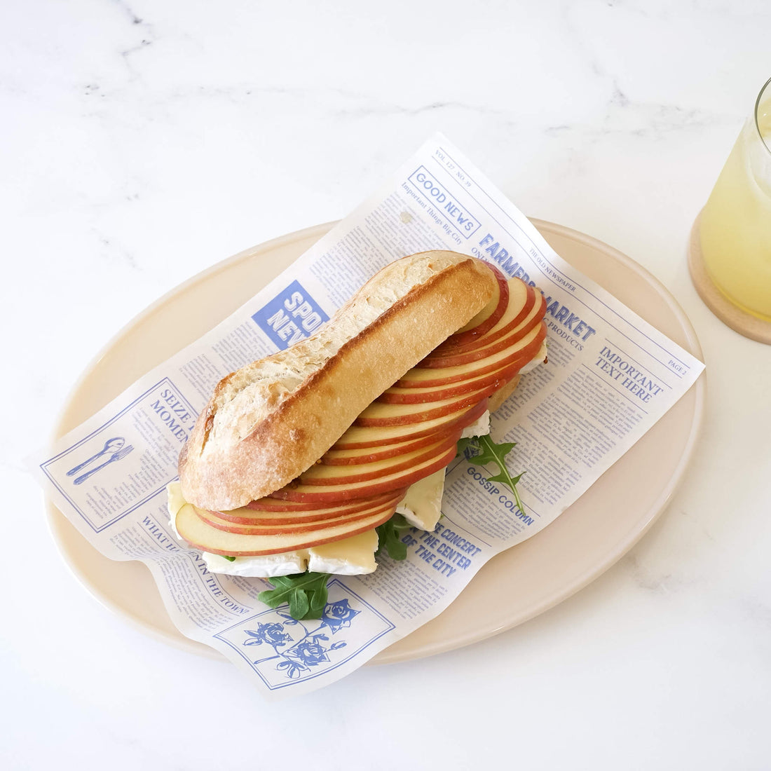 apple brie cheese sandwich on newspaper printed deli paper in blue