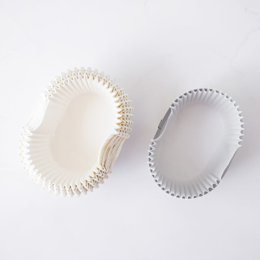 Two white cupcake liners on a light gray background