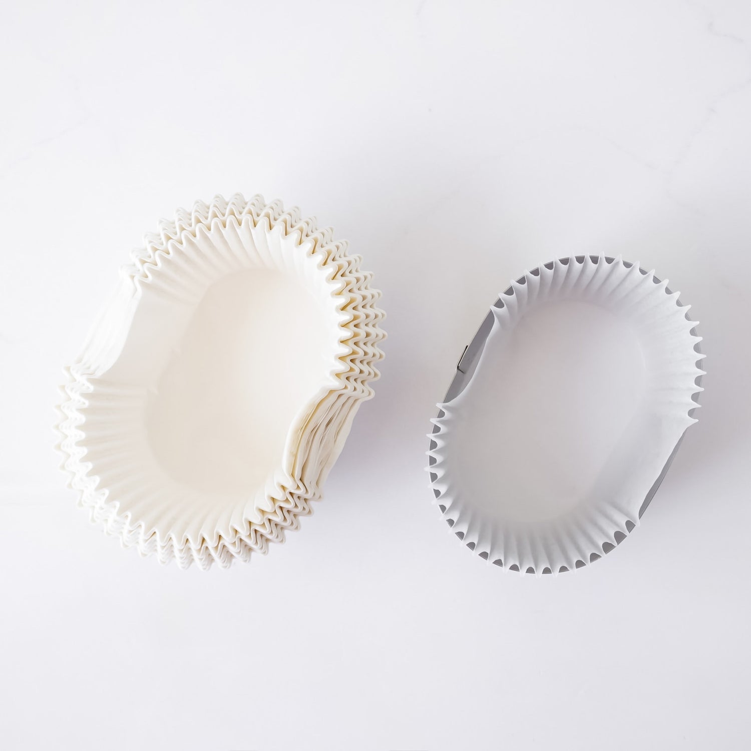Two white cupcake liners on a light gray background