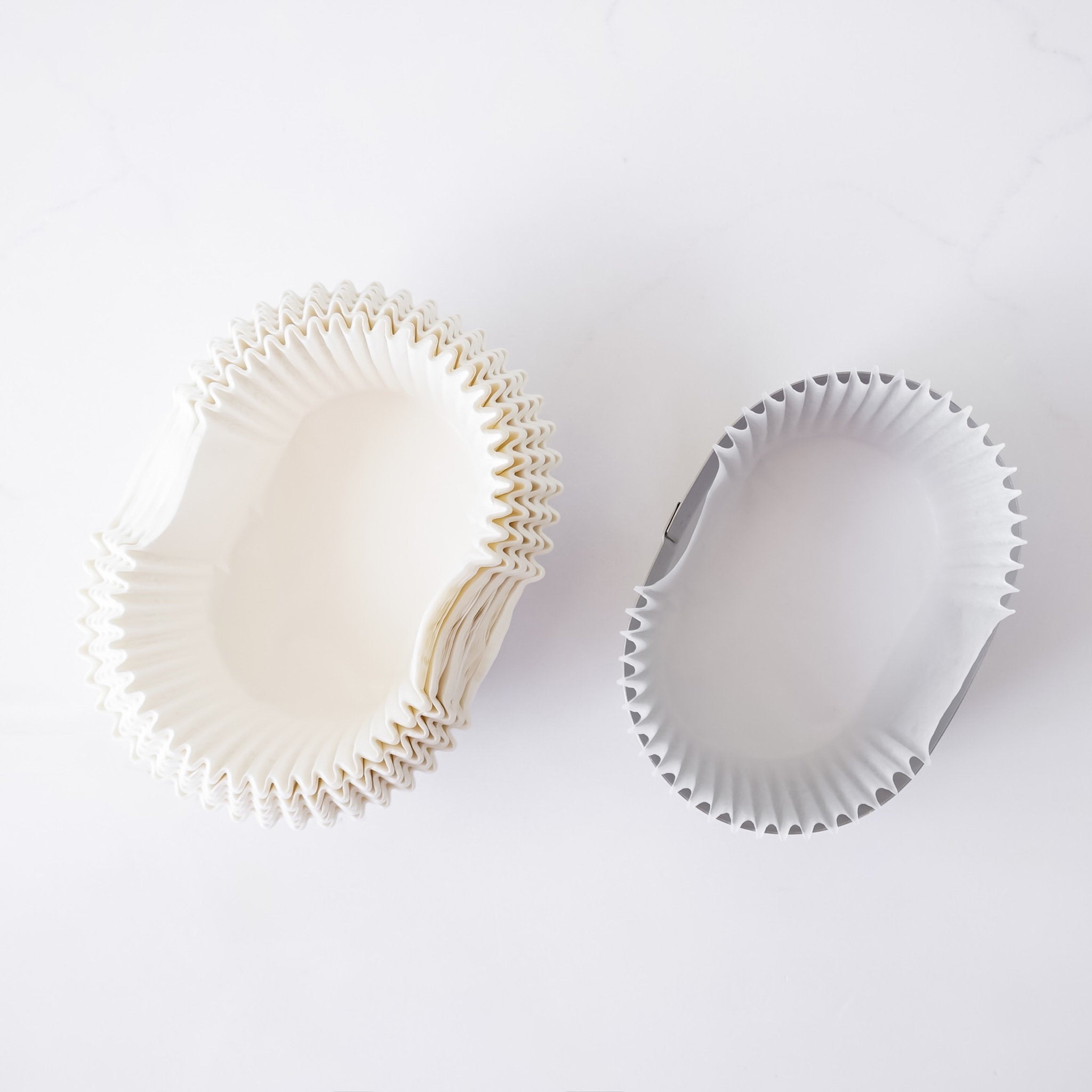 Two white cupcake liners on a light gray background