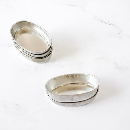 Stack of silver oval financier molds on a white surface