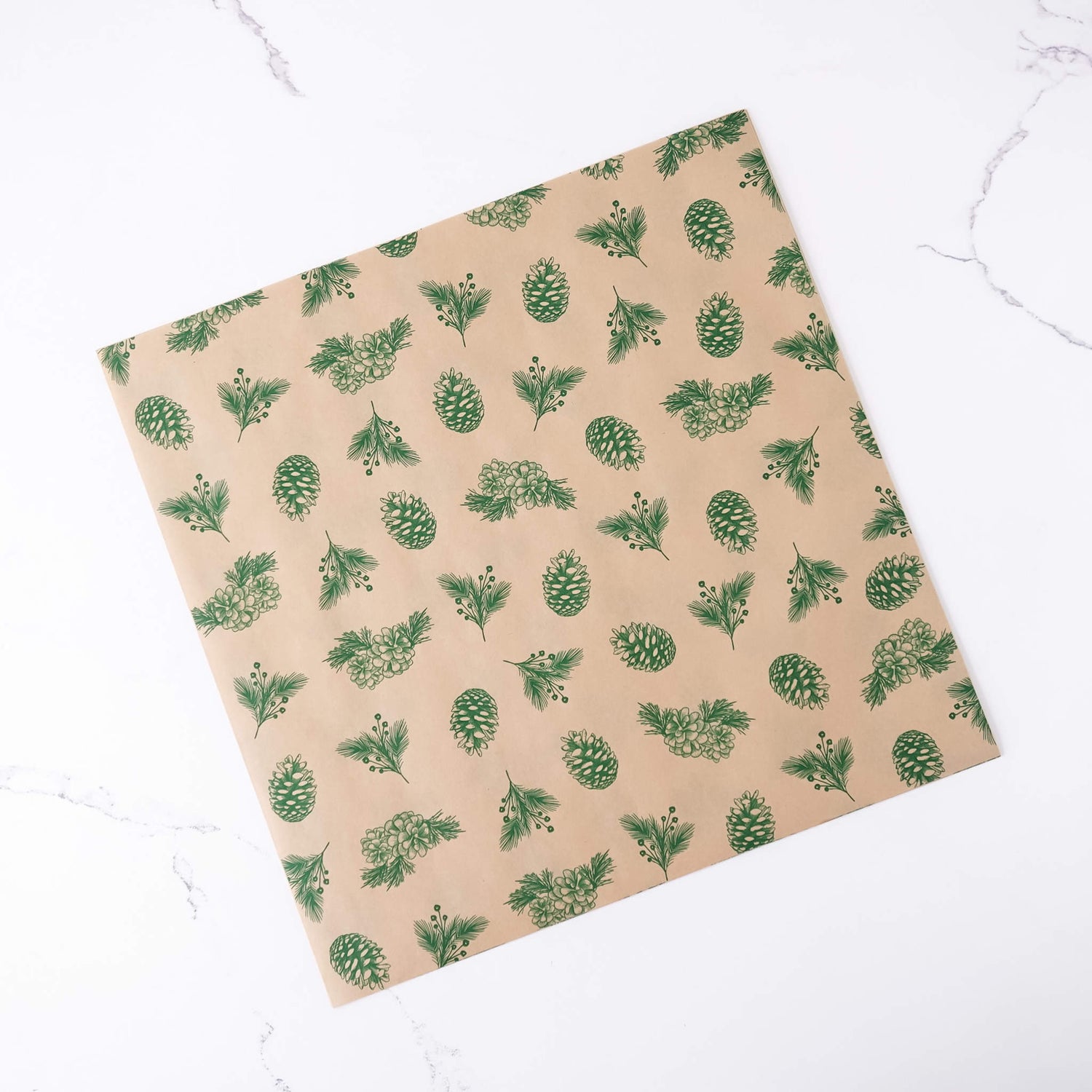 Beige paper with green pine cone pattern on a white marble background