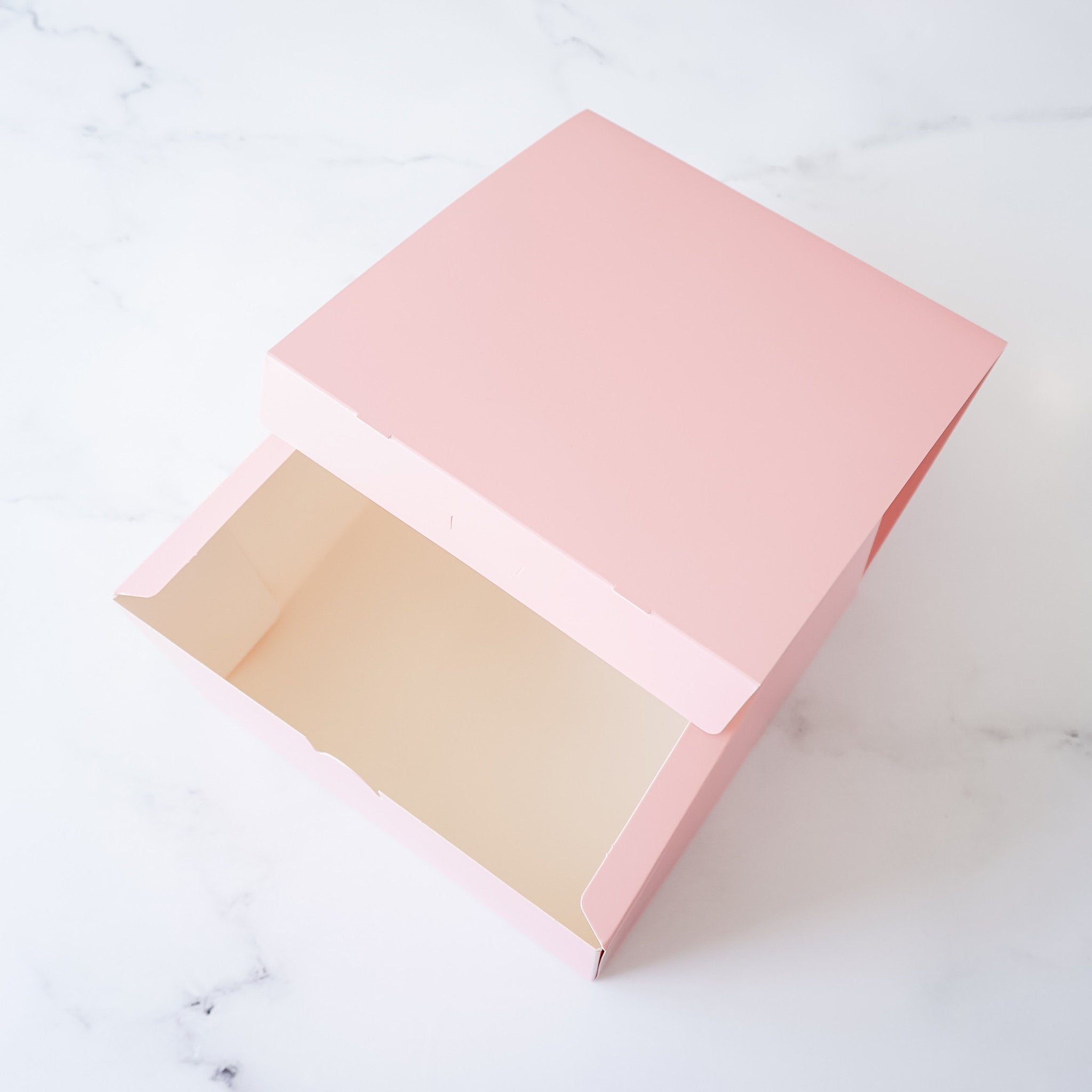 A pink cardboard box with the lid open. The box is empty.