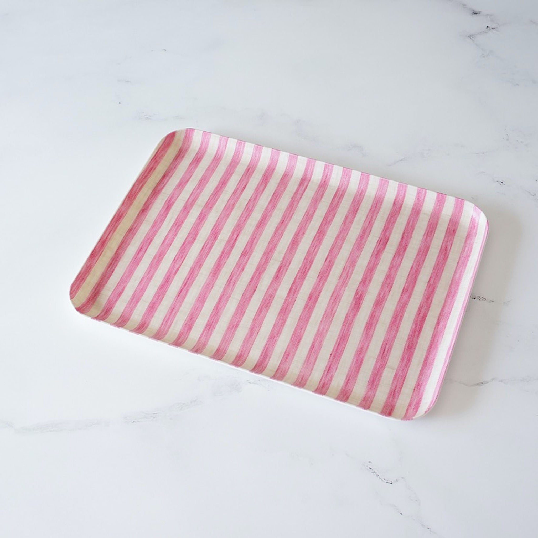 A pink striped linen coated tray on a marble surface.