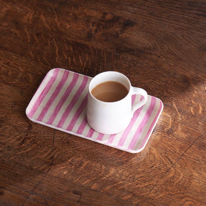 a cup of coffee on a pink tray