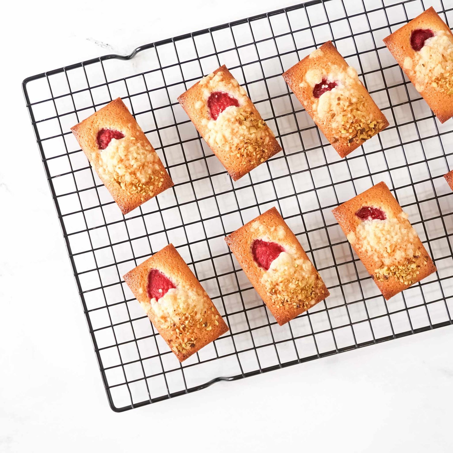 Small baked goods with strawberry filling on a cooling rack