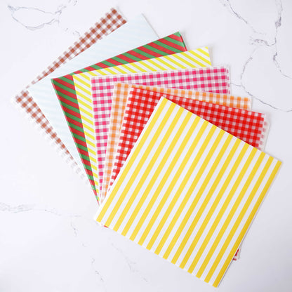 Set of colorful deli paper sheets with stripes and checkered patterns on a white surface.