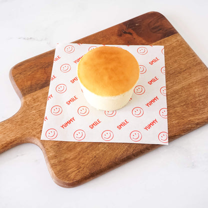 Baked good on a piece of deli paper with smiley faces on a wooden cutting board