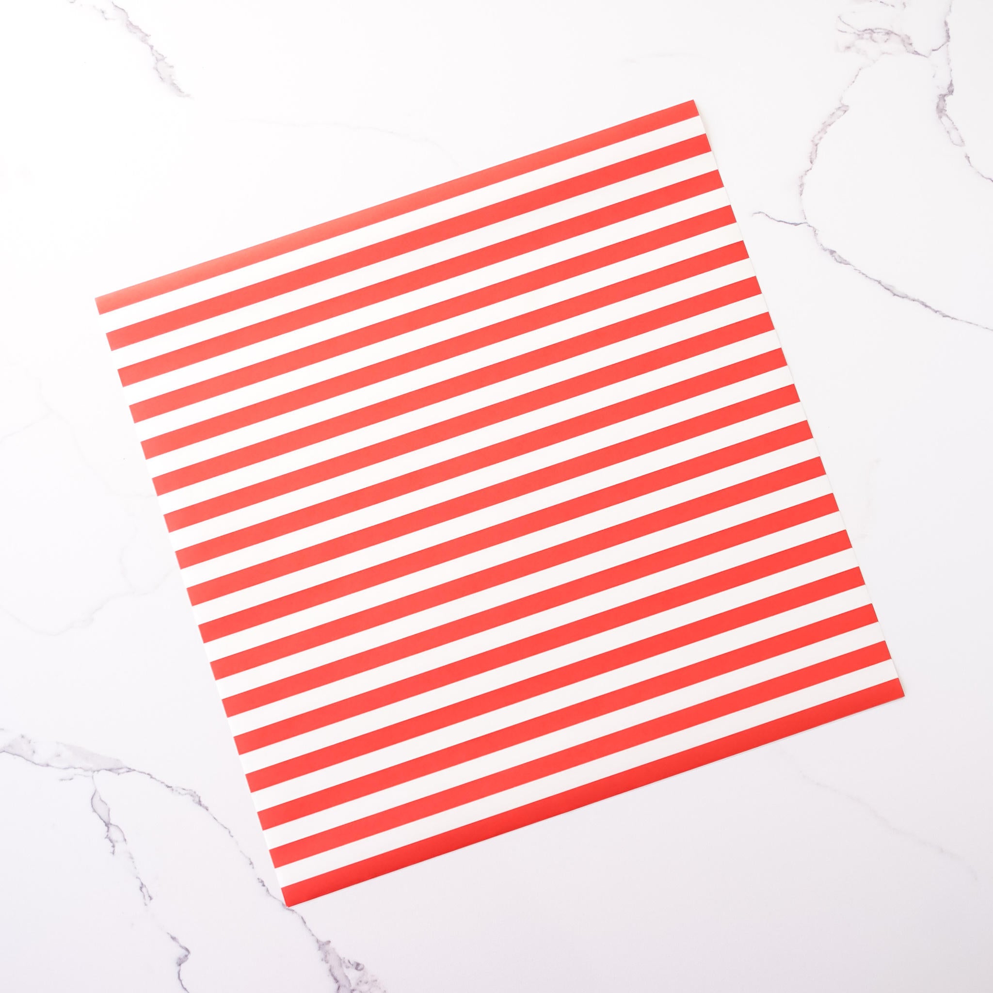 A sheet of red and white striped deli paper laid out on a marble surface.