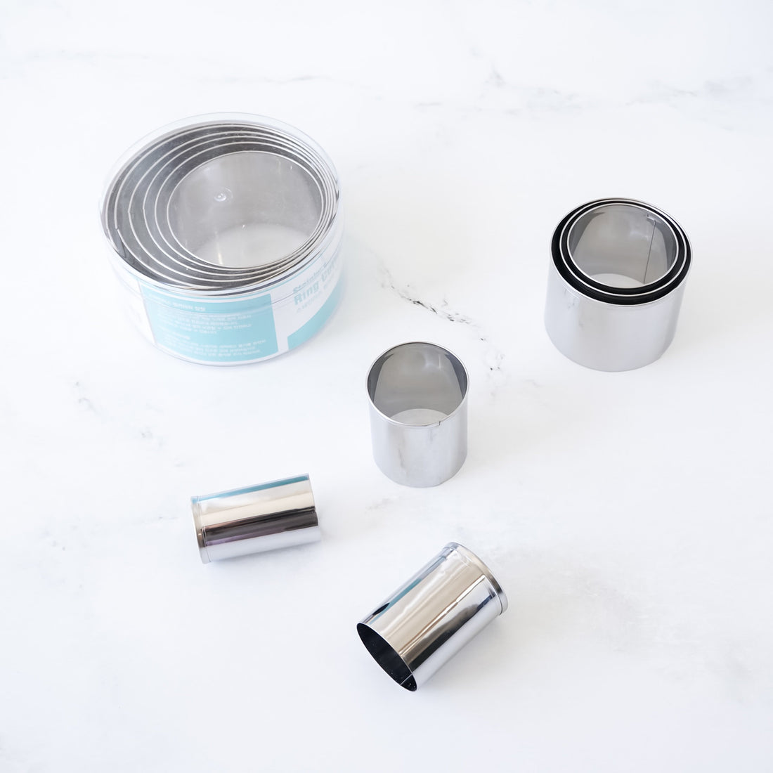 Stainless steel round cookie cutters on a white surface