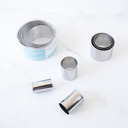 Stainless steel round cookie cutters on a white surface