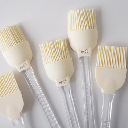 Set of five silicone basting brushes with clear handles on a white background