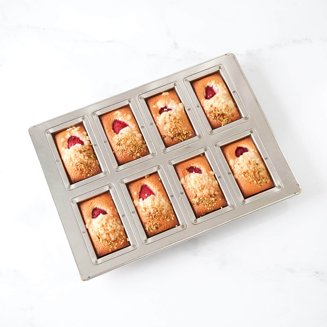 Baked goods in a metal financier mold on a white background