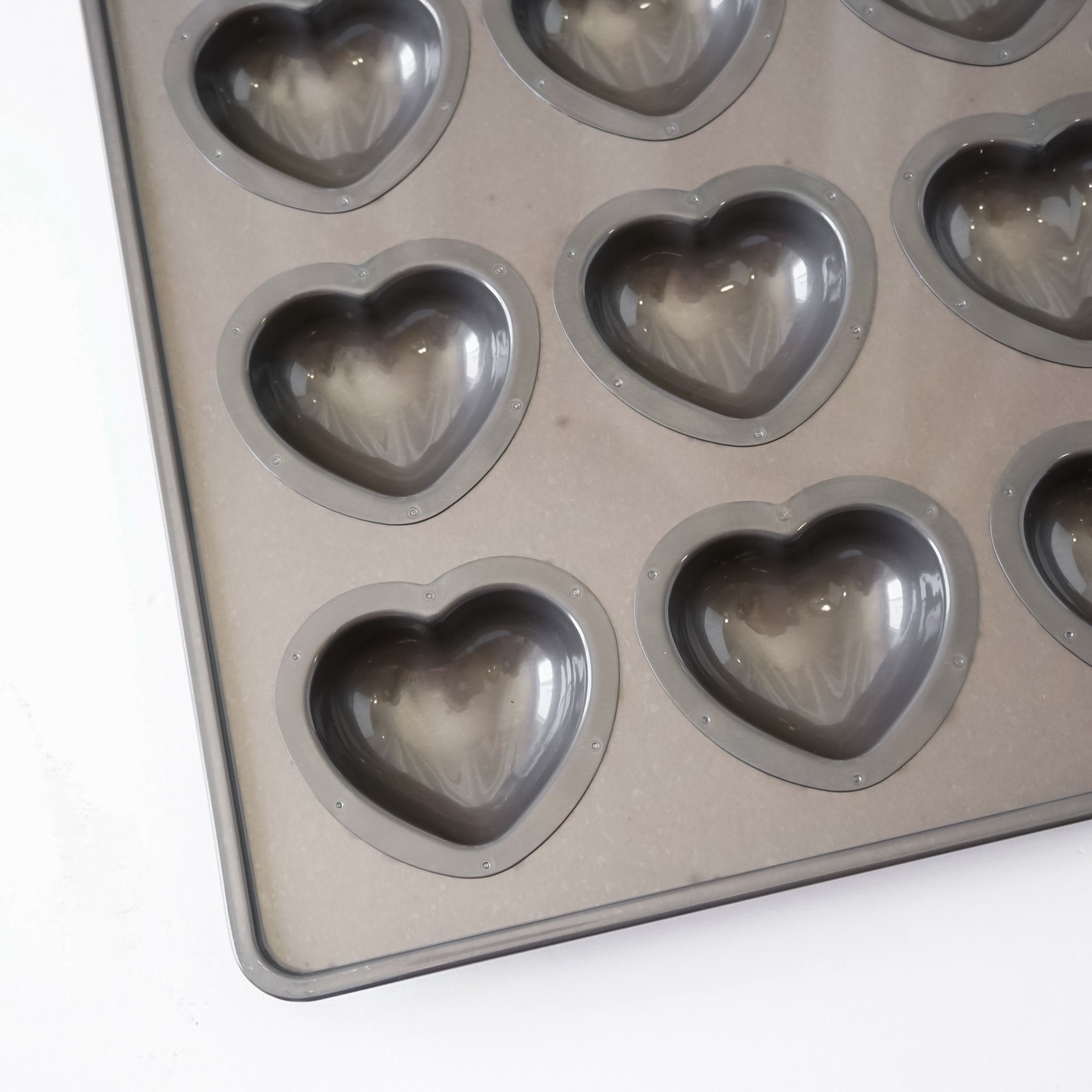 Heart-shaped metal mold tray with multiple heart-shaped cavities, photographed on a plain white background.