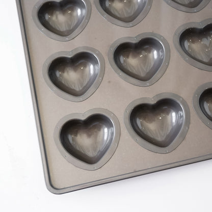 Heart-shaped metal mold tray with multiple heart-shaped cavities, photographed on a plain white background.