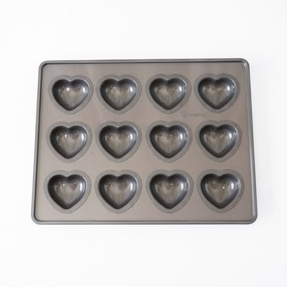 A rectangular gray heart-shaped mold tray with twelve heart-shaped cavities, photographed from above on a plain white background.