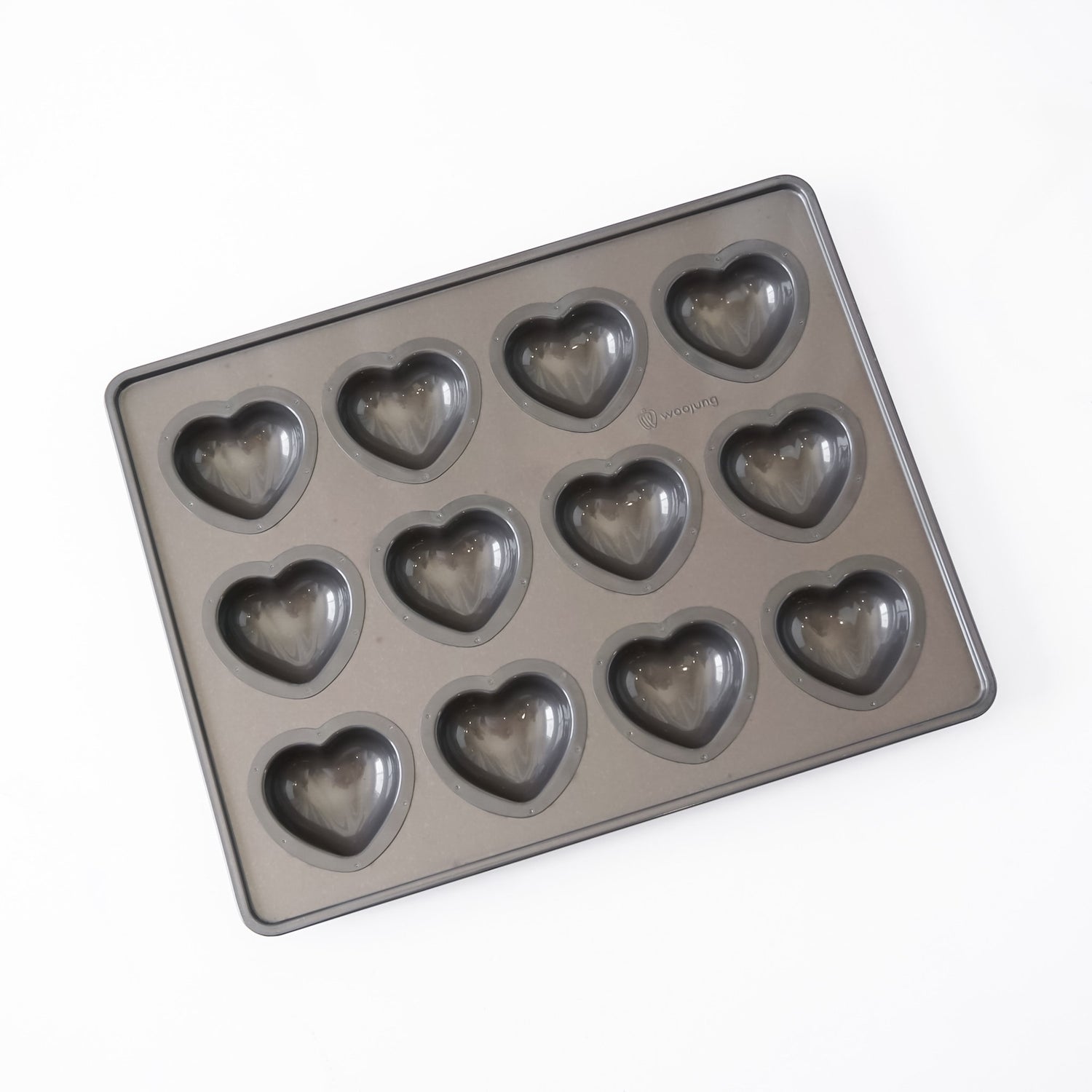 A rectangular non-stick baking mold with 12 heart-shaped cavities, shown at an angle on a plain white background.