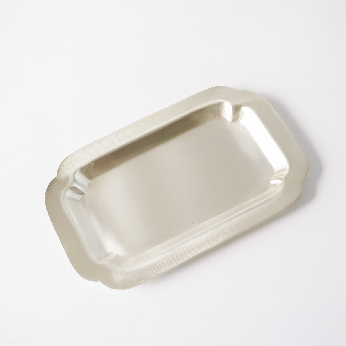 A rectangular silver metal tray with scalloped edges, photographed from an elevated angle on a clean white background.