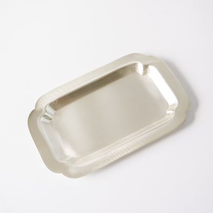 A rectangular silver metal tray with scalloped edges, photographed from an elevated angle on a clean white background.