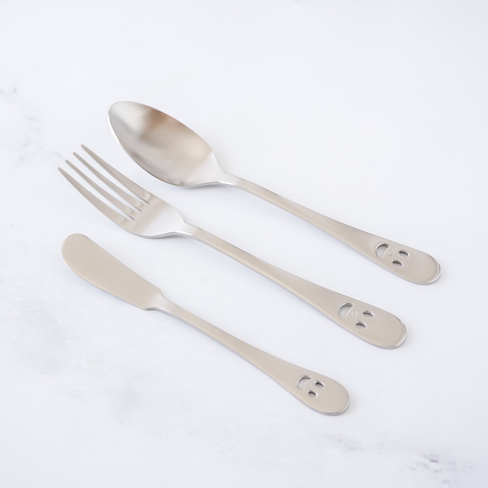 Set of silver cutlery including a spoon, fork, and knife on a white background