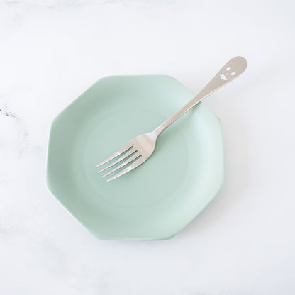 Mint green plate with a fork on a white background