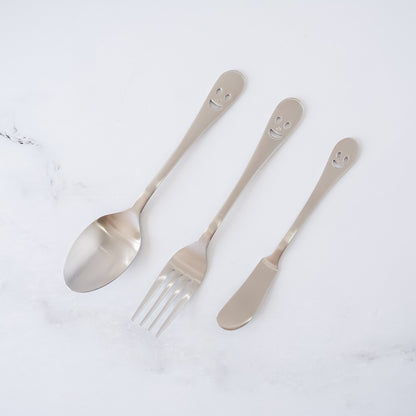 Set of three silver smiley face cutlery  including a spoon, fork, and knife on a white background