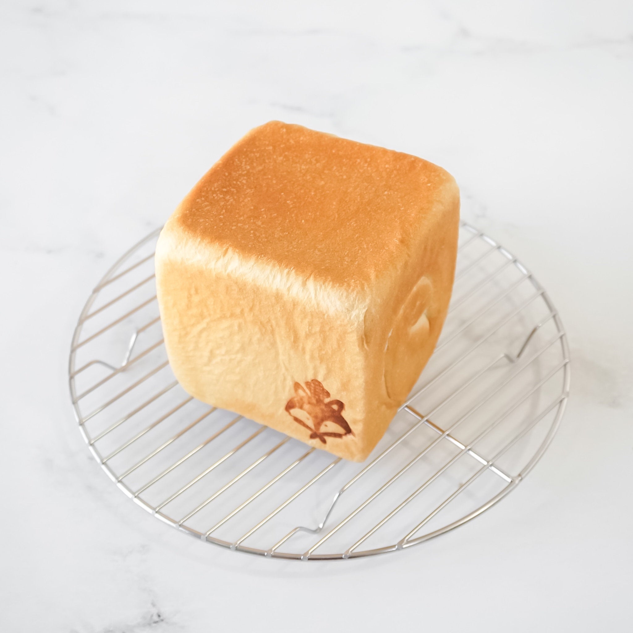 Loaf of bread on a cooling rack with a white background